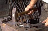 Blacksmith works with tools of his trade.