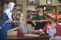 Ladies enjoy a cup of tea while examining the latest goods at the Millinery Shop.