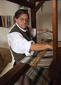 Weaver Max Hamrick weaves cloth on the oak and pine four-shaft cantilever loom.