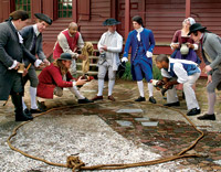 In town and country, for merchant and farmhand, cockfighting—a bloody and usually fatal affair—was close to a national sport in eighteenth-century America, with betting a prime part of it. Colonial Williamsburg interpreters gather round the ring, from left: Tom Hay, Dennis Watson, Bill Rose, James Ingram, Mark Hutter, Dan Moore, Ayinde Martin, Carrie McDougal, and Jay Howlett.