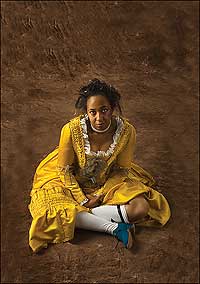 Actor-interpreter Hope Smith poses in a bright yellow silk satin Brunswick—a style of matching petticoat and sack-back jacket—decorated with blue silk and organdy bows and finished with blue-silk-covered heeled shoes by Sara Juniper.
