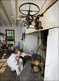 In the kitchen of Colonial Williamsburg's Governor's Palace, Historic Foodways interpreter Rob Brantley bastes a bird roasting on the spit.