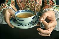 With the delicacy of a gentlewoman, Cathy Hellier offers a guest a fine-china cup of tea and silver spoon.