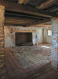 The basement kitchen of seventeenth-century Bacon's Castle in Surry County, Virginia, with brick hearth and timber lintel.