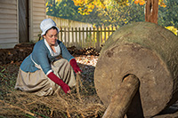 Weaver apprentice Gretchen Johnson re-enacts laying flax to be crushed by a hemp stone.