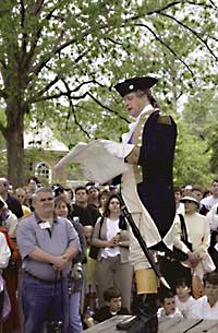 >Interpreter Mark Muller, portraying George Washington, addresses a crowd of Colonial Williamsburg visitors from a platform behind the Governor's Palace.
