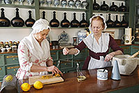 Robin Kipps holds the scale as Sharon Cotner weighs orange peel used in an 18th-century treatment re-created at the Pasteur & Galt Apothecary Shop.