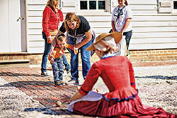 Interpreters behind the James Geddy House lead games and activities for children.
