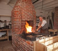 Master blacksmith Ken Schwarz at the forge of the recently reconstructed James Anderson Blacksmith Shop and Armoury