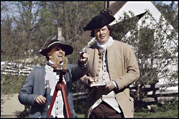 Colonial Williamsburg's Willie Balderson, portraying the surveyor, and Brian Simpers, serving as his tally man, determine the bearing of a survey line with a wooden plane surveying compass