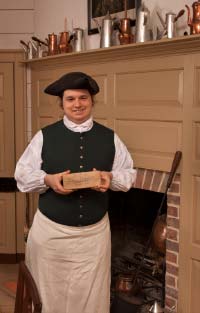 Alan Ramsey holds a pressed cake of chocolate wrapped in paper, a common form it was sold in the eighteenth century.