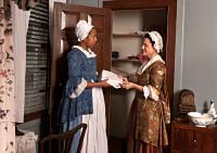 Carolyn Wilson portrays Betty Randolph inspecting linens, with Hope Smith interpreting Randolph family servant Eve.